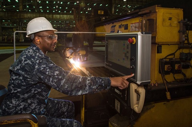 Cmdr. Dave Murray, production officer for the U.S. Navy’s DDG 51 program, presses the button to start fabrication of the Ingalls-built destroyer Frank E. Petersen Jr. (DDG 121). Photo by Lance Davis/HII